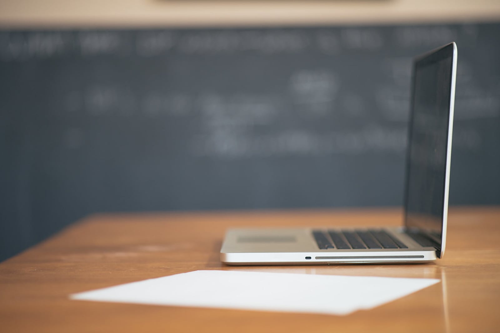 A laptop on a tidy desk beside a coffee mug.